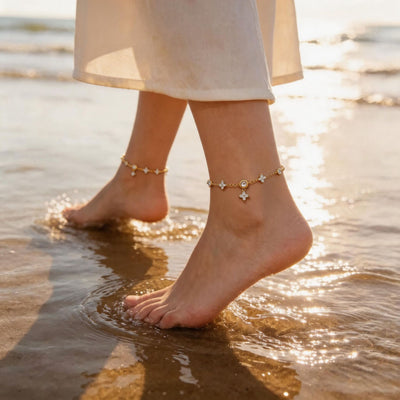 Gold four-leaf clover chain anklets worn on both ankles at the beach