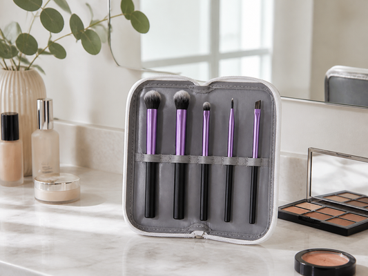 Purple eye makeup brush starter set in a gray case on a bright vanity