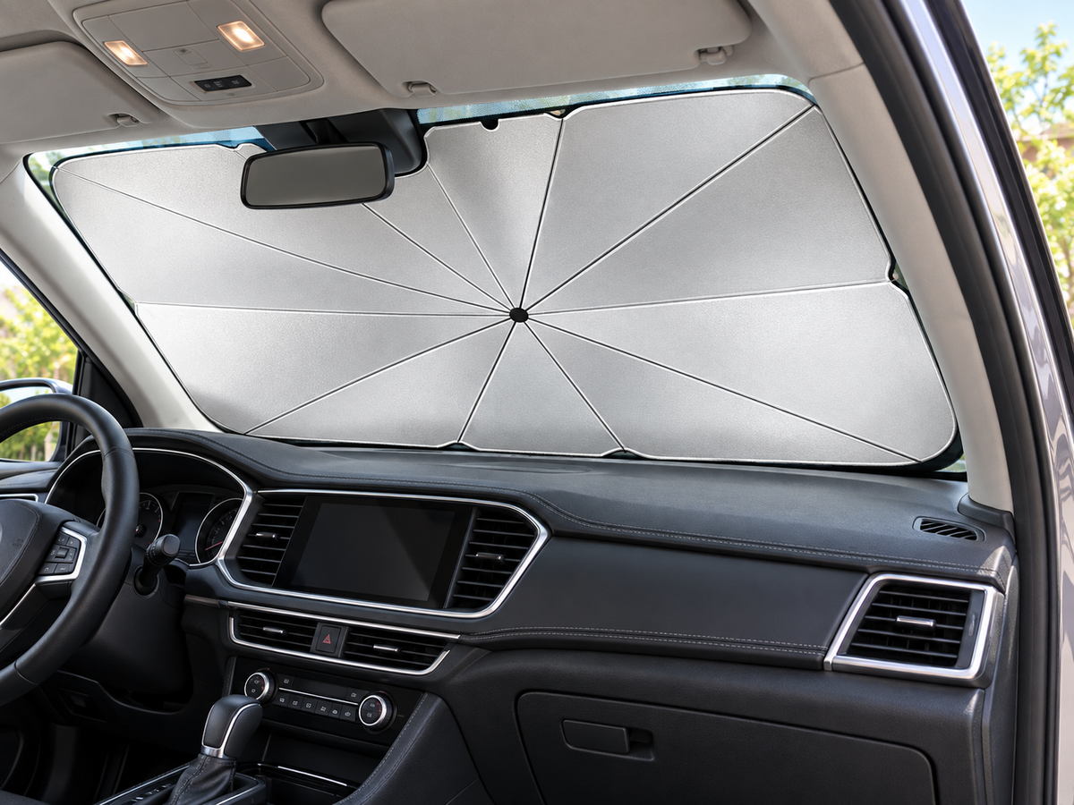 Silver folding windshield sun shade fitted inside a parked car