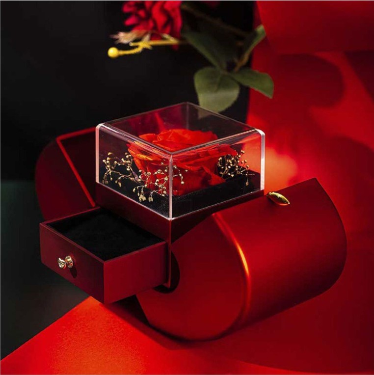 Open red apple rose gift box with preserved-look rose on a dark red background