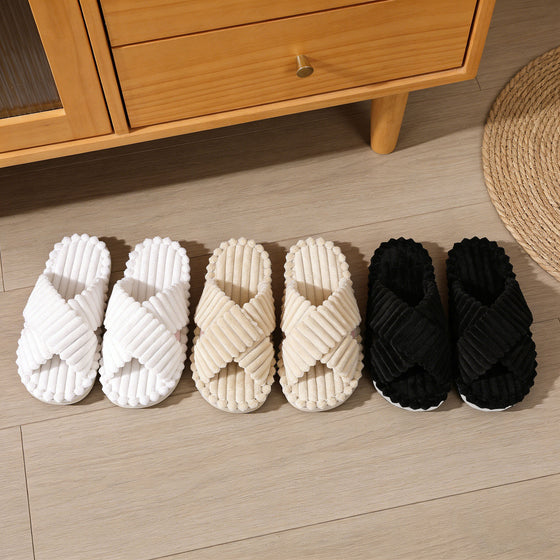White, beige and black cross-strap slippers lined up on a floor