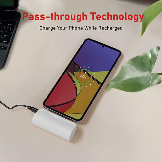 White mini power bank plugged into a phone on a desk, pass-through charging