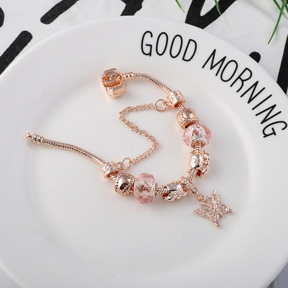 Charm bracelet with a butterfly pendant on a white plate