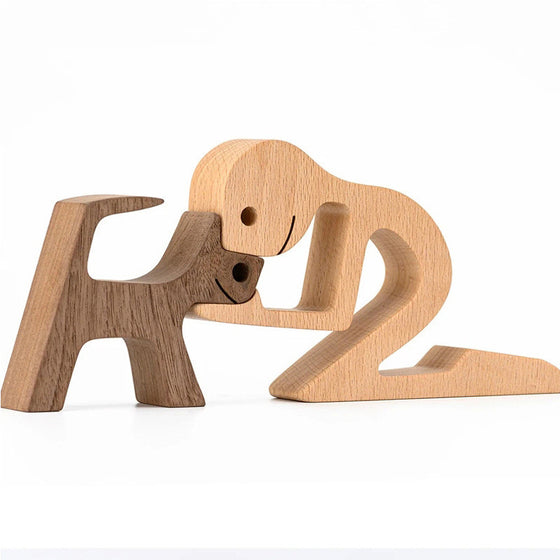 Wood carving of a dog beside a kneeling figure, light natural wood