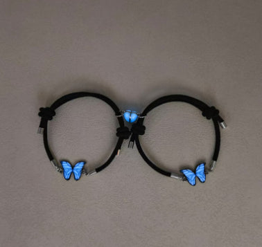Pair of black cord bracelets with glowing blue butterfly charms