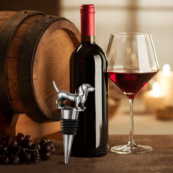 Silver dachshund wine stopper in front of a wine barrel and glass