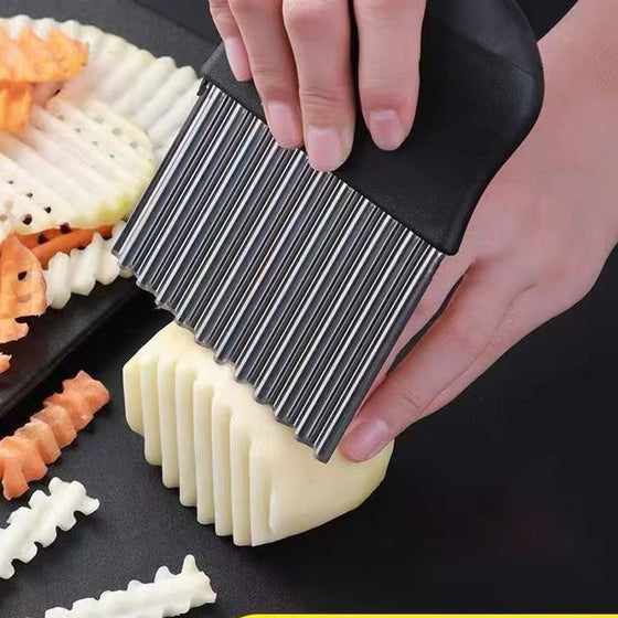 Hands pressing the crinkle cutter into a potato