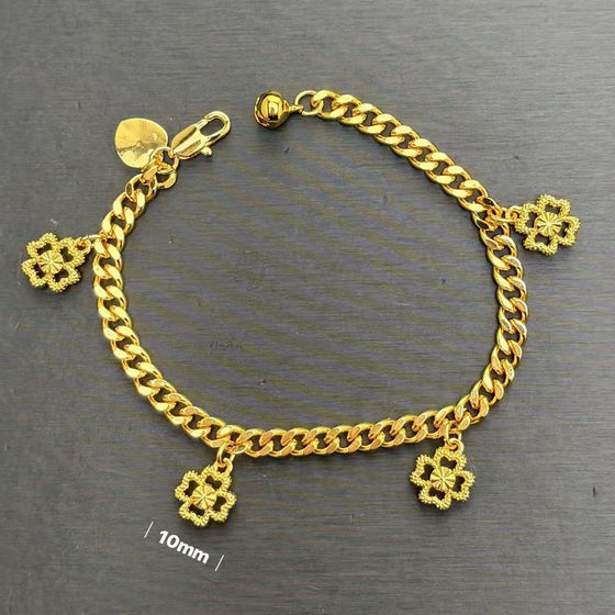 Gold four-leaf clover charm curb chain bracelet with lobster clasp on a grey background