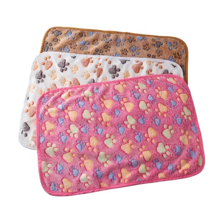 Three paw print pet blankets in brown, cream and pink laid out