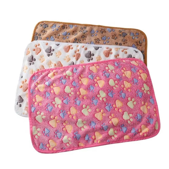 Three paw print pet blankets in brown, cream and pink laid out