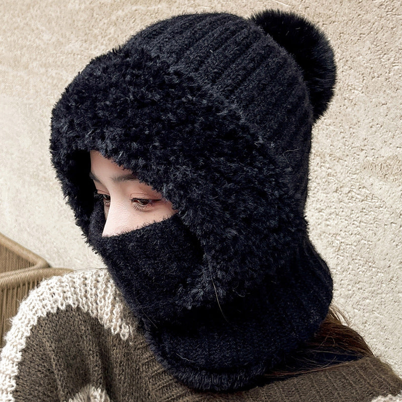 Woman wearing a black knit hood with pom pom and plush trim