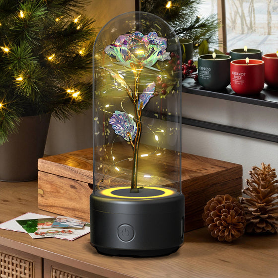 Blue rose LED lamp in a glass dome on a black speaker base in a living room