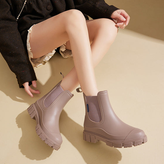 Mauve rain boot with a lug sole on a seated woman