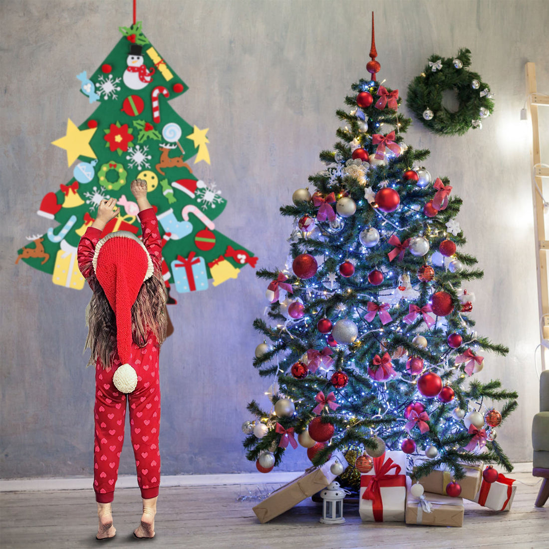 Child in a Santa hat decorating a wall-hung felt Christmas tree beside a real tree