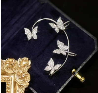 Gold-tone butterfly ear cuff on dark velvet, close-up