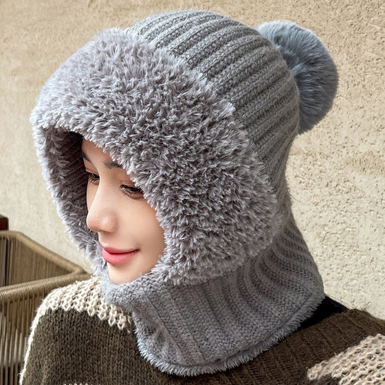Woman wearing a gray knit hood with plush face trim and pom pom