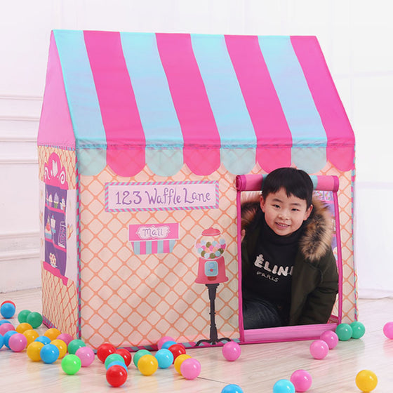 Boy looking out of the window of a pink striped play tent