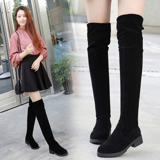 Black suede over-the-knee boots worn with a skirt