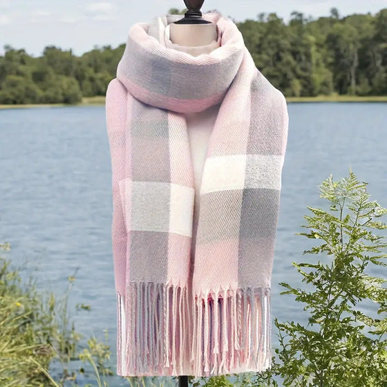 Pink plaid winter tassel scarf on a mannequin beside a lake