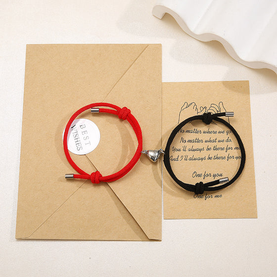 Red and black magnetic couple bracelets on a kraft envelope with a card