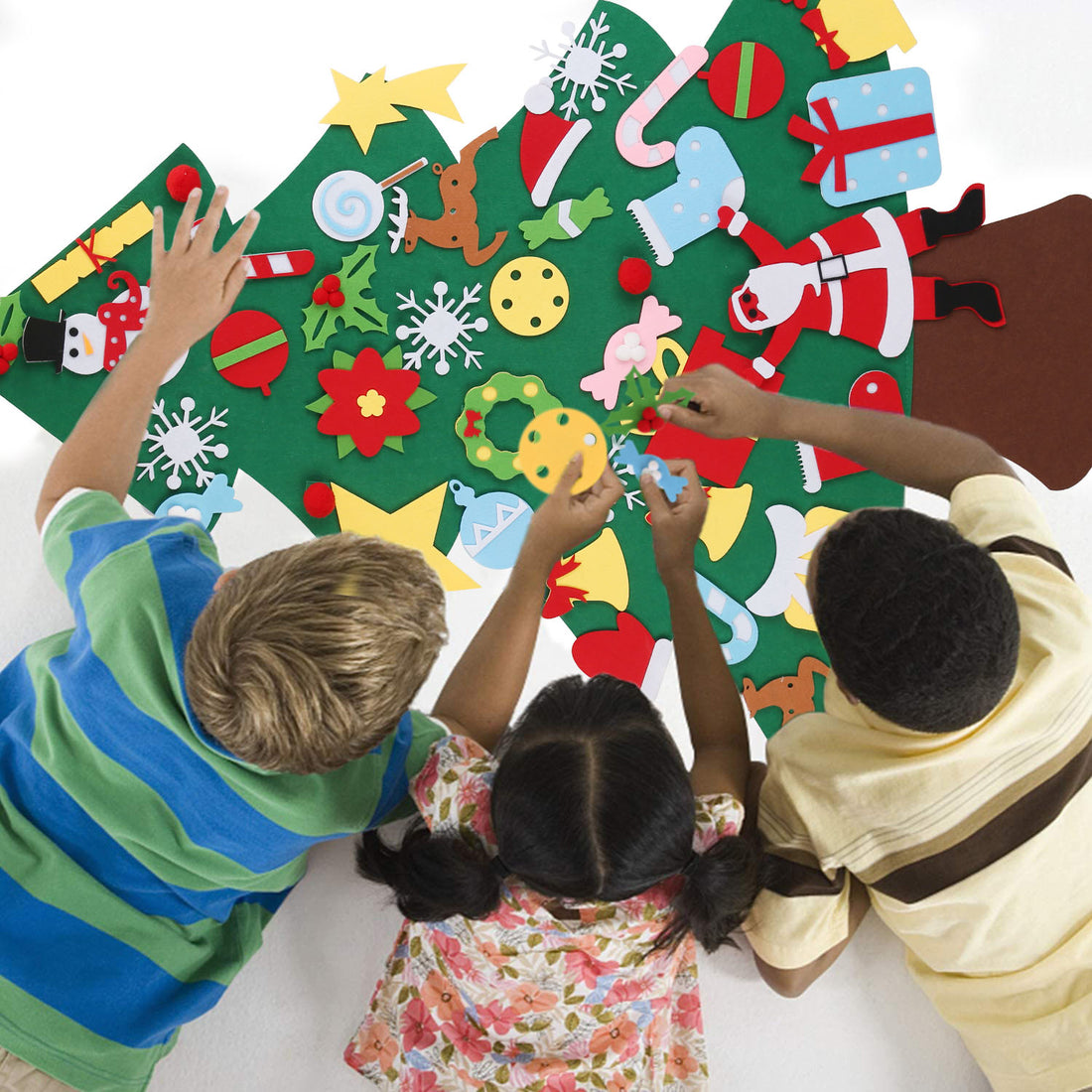 Three kids decorating a felt Christmas tree on the floor
