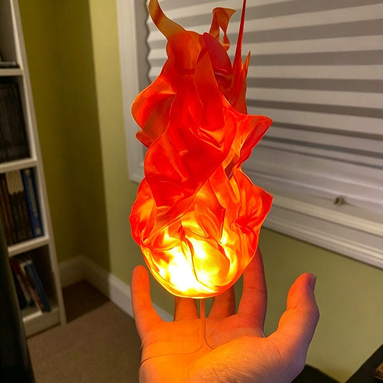 Hand holding a glowing orange fireball lamp in front of blinds
