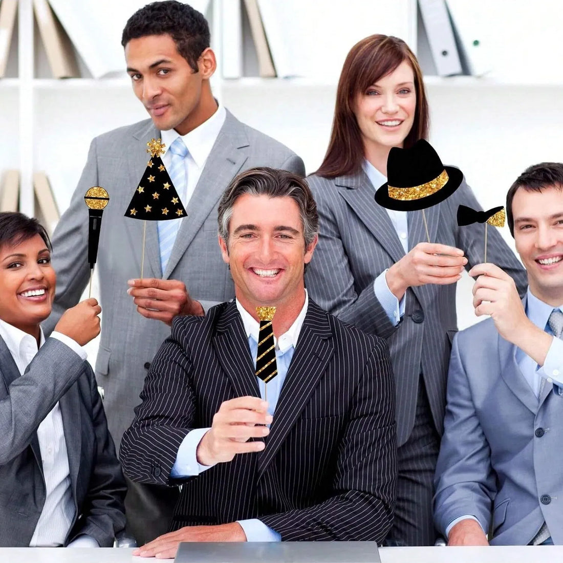 Office party group posing with black and gold photo booth props