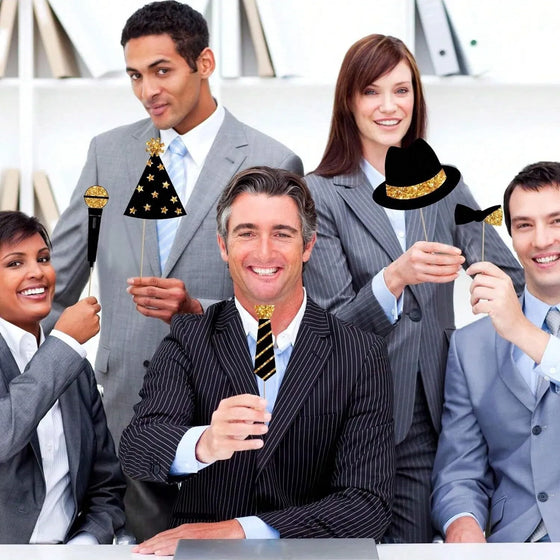 Office party group posing with black and gold photo booth props