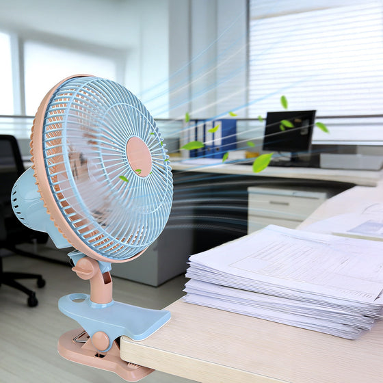 Beige and blue clip-on fan clamped to an office desk
