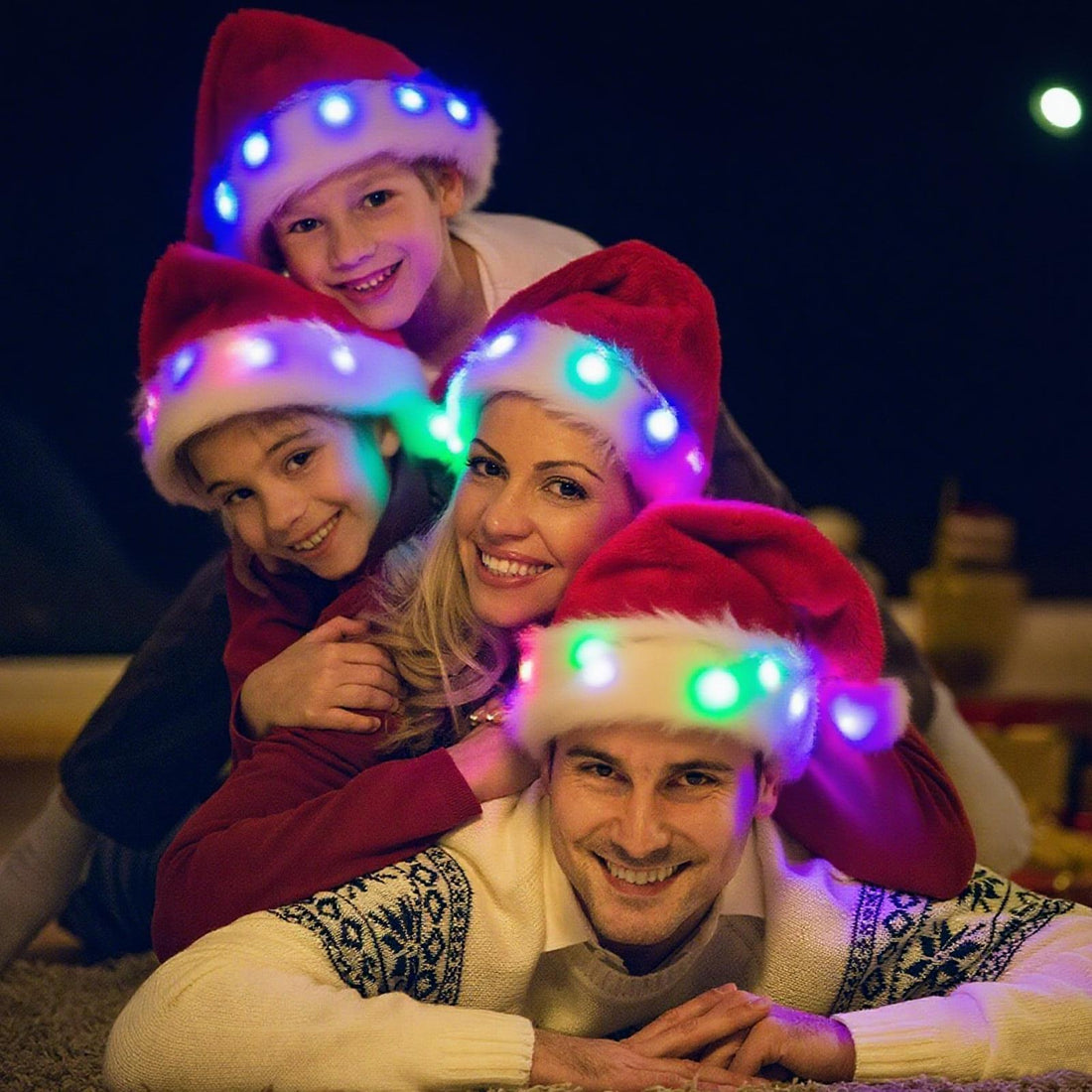 Family wearing glowing LED Santa hats at night