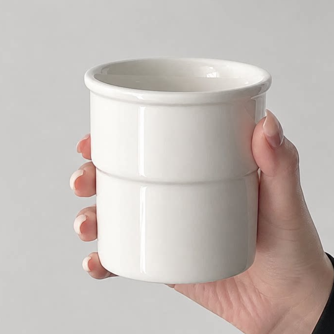 Hand holding a white ceramic cup