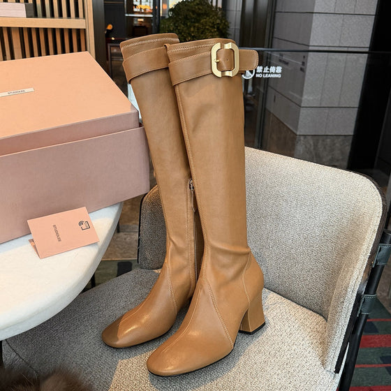 Tan knee-high boots with a gold buckle strap and block heel