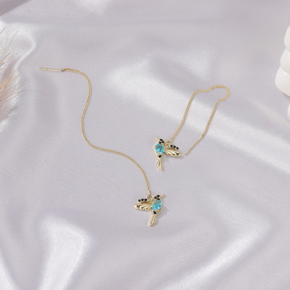 Hummingbird earrings laid on white satin