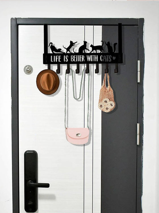 Cat hook rack on a dark door holding a hat and bags