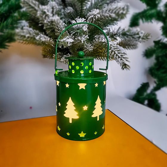 Green wrought iron Christmas lantern with tree and reindeer cutouts, lit