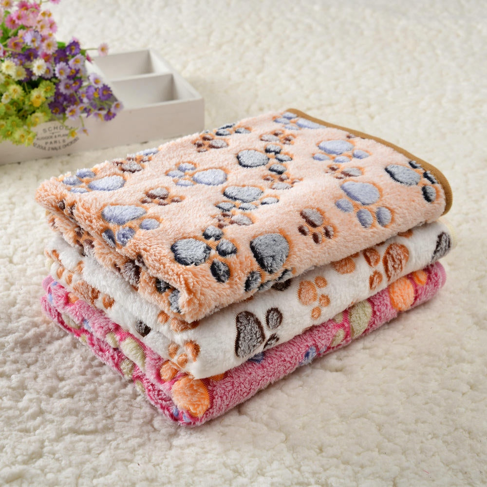 Three folded paw print pet blankets in tan, cream and pink