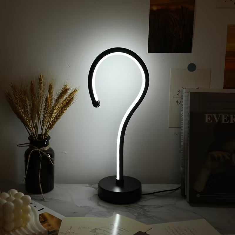 Question mark lamp glowing cool white on a desk