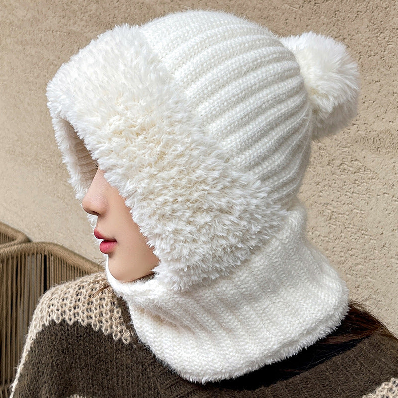 Woman wearing a white knit hat-scarf hood with plush trim and pom pom