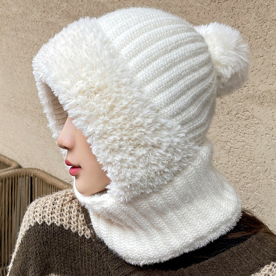 Woman wearing a white knit hat-scarf hood with plush trim and pom pom