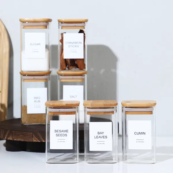 Stacked square glass spice jars with bamboo lids and labels