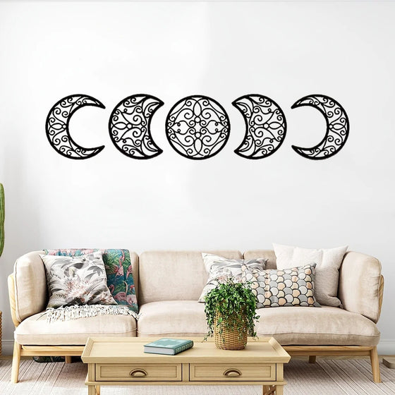 Five black metal moon phase pieces above a sofa