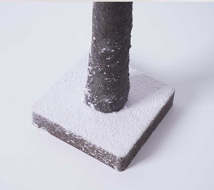 Close-up of the snow-dusted birch trunk and base of the LED tree