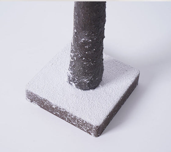 Close-up of the snow-dusted birch trunk and base of the LED tree
