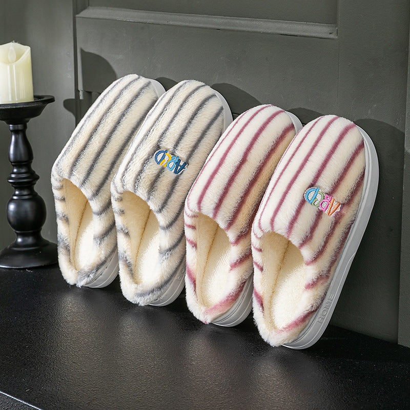 Four pairs of striped plush slippers lined up against a dark wall