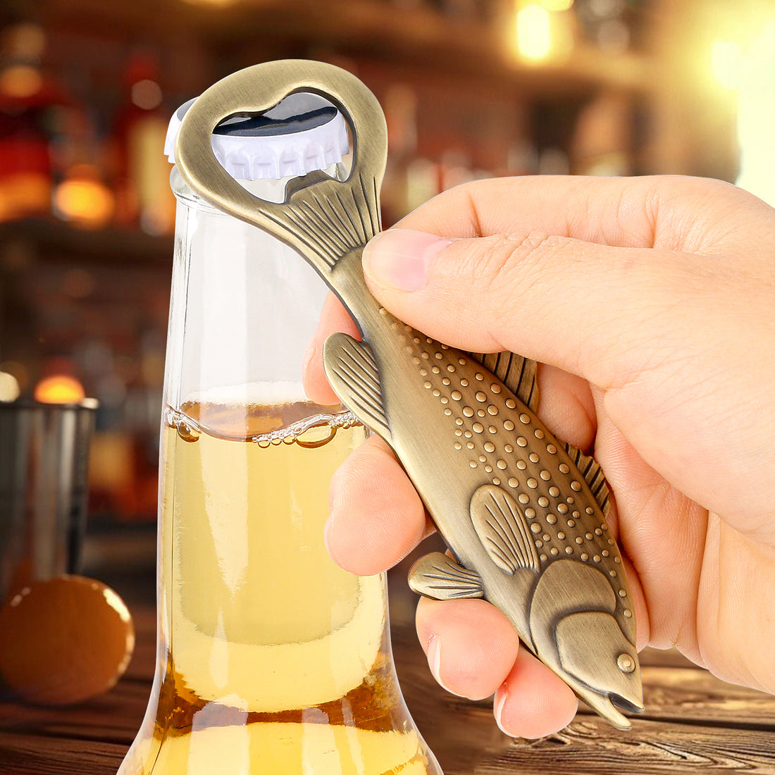 Hand using the bronze bass fish opener on a beer bottle
