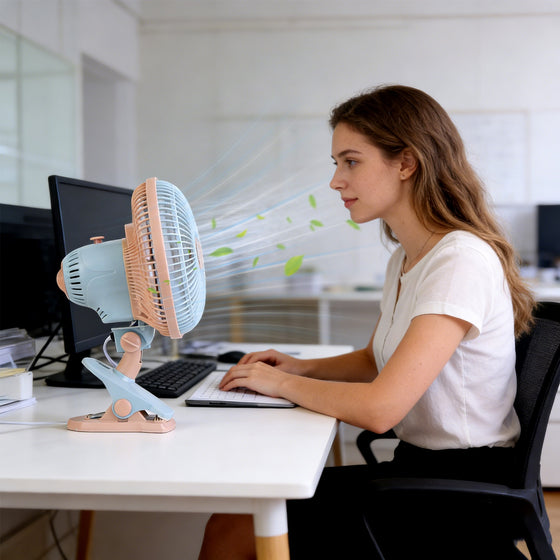 Woman working at a computer with a clip-on fan on the desk