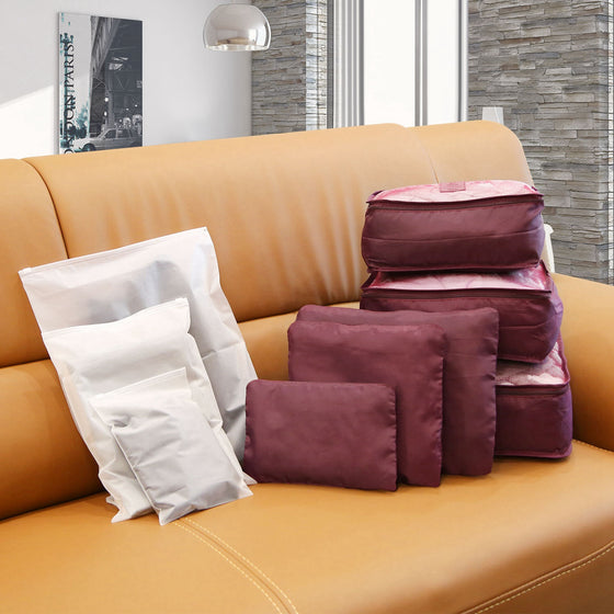 Burgundy packing cubes and white bags on a sofa