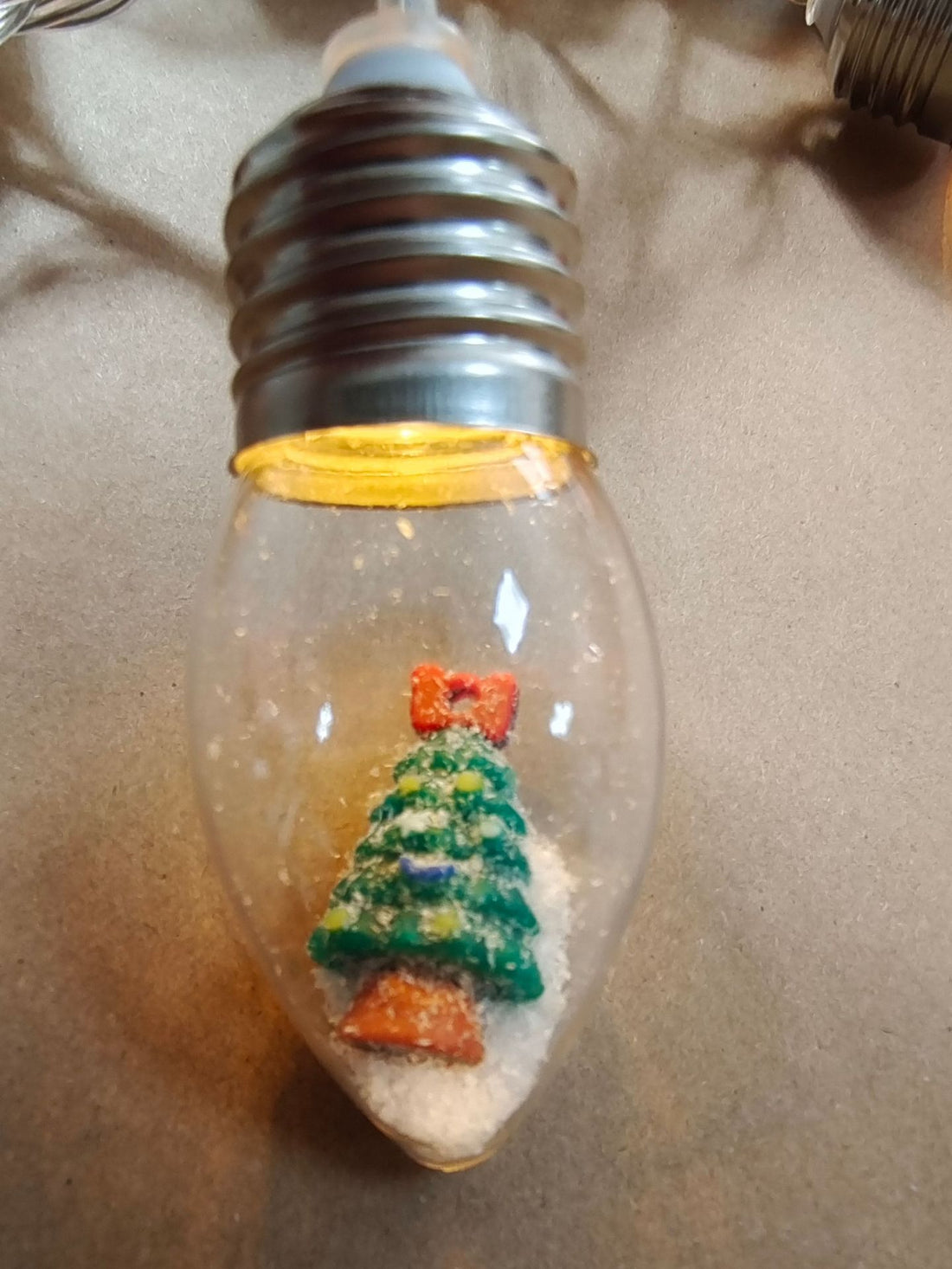 Clear bulb string light with a miniature Christmas tree figure inside