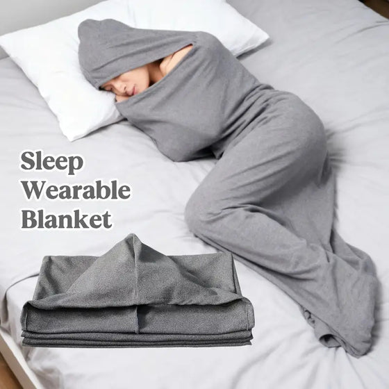Person lying in bed wrapped in a gray wearable hooded sleep pod blanket