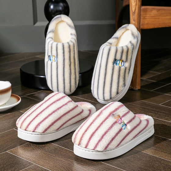 Striped plush slippers standing upright and lying flat on a wooden floor